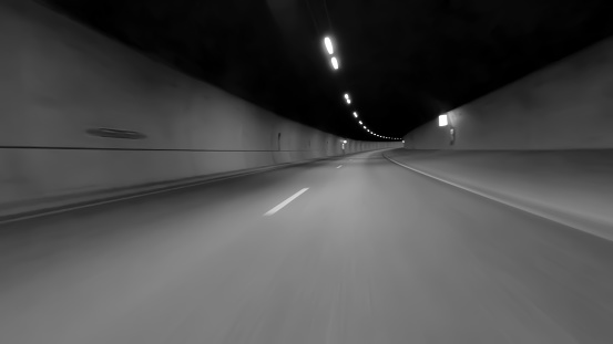 Speeding through a asphalt Motorway Tunnel with high speed motion blur. Black and white tint long exposure.