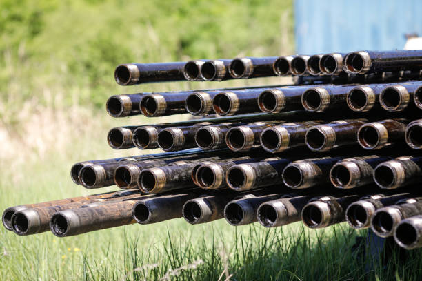 tuyaux de forage d’engins pétroliers empilés avec des travailleurs de l’industrie pétrolière en arrière-plan. industrie pétrolière et gazière. prise de pompe à pétrole brut sur un champ pétrolifère. forage de puits de pétrole et de gaz. - oil rig sea drill petroleum photos et images de collection