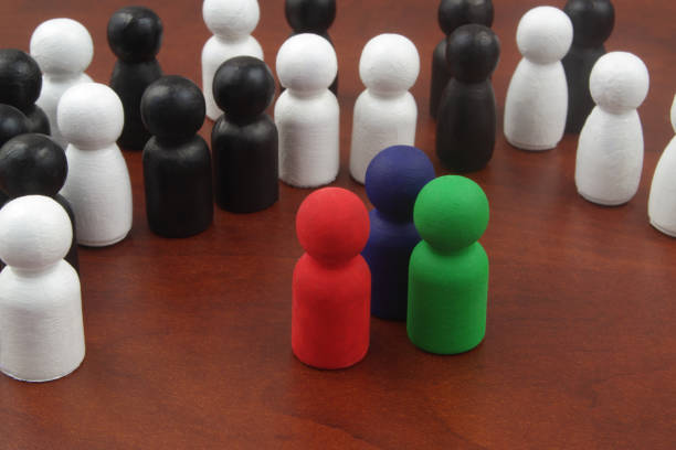 czerwone, niebieskie i zielone drewniane figury jako przywódcy stojący w pobliżu tłumu białych i czarnych postaci. - surrounding leadership organization meeting zdjęcia i obrazy z banku zdjęć