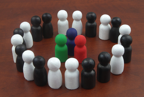 Colored people figures surrounded by black and white figures. Concept of business leadership.