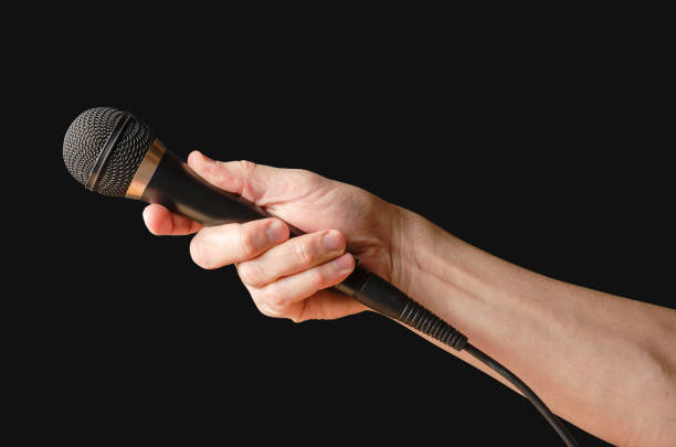 istock Microphone in hand closeup. Isolated on a black background 1398045023