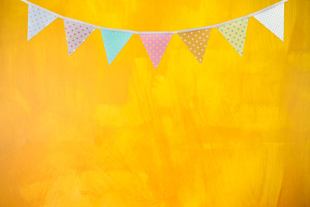 istock Colorful flag garland on yellow wall texture background 1398045056
