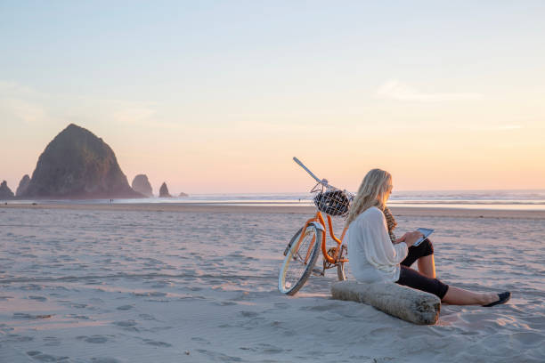 une femme mûre utilise une tablette numérique, sur la plage - cycling bicycle healthy lifestyle green photos et images de collection