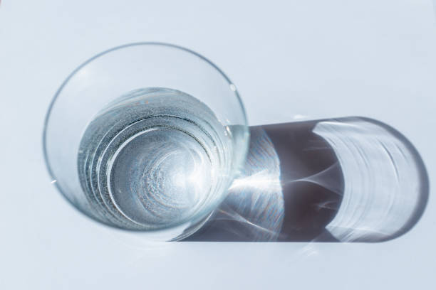istock Water glass with sun shadows on white background.Sunlight through glass.Top view. 1398045987