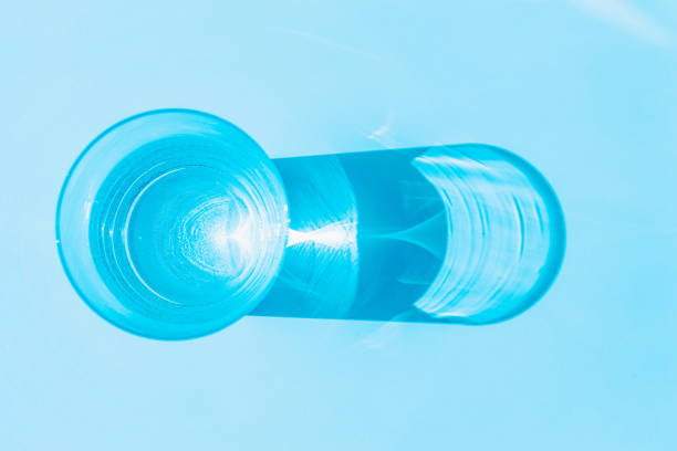 istock Top view clear water glass with water on white table.Sunlight through blue glass. 1398045991