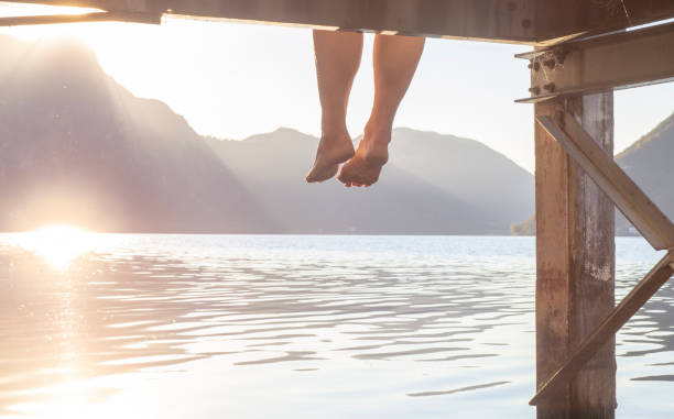 istock Woman's legs dangle from pier, by lakeshore 1398045993