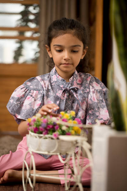 Adorable little girl admiring fresh flowers at home