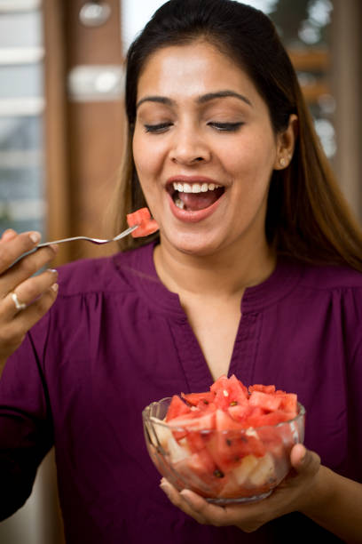 Happy woman eating watermelon at home stock photo