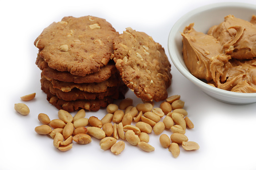 Peanut butter cookies on a plate with peanuts and peanut butter cream on white background. Traditional american dessert