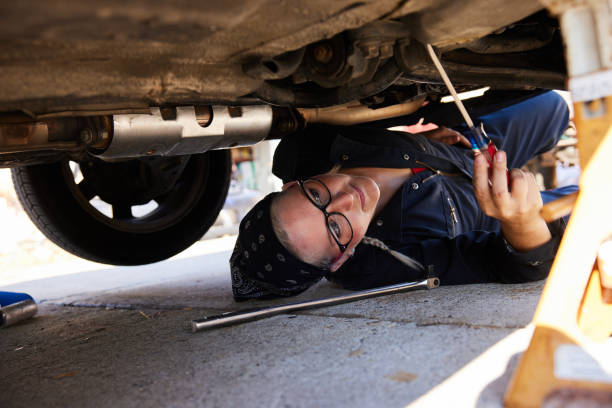 istock Young female mechanic working under a car outside 1398054289