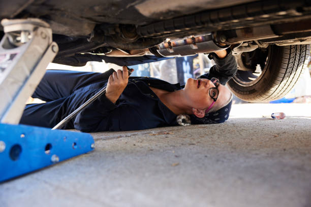 istock Young female mechanic working on the underside of a car 1398054308