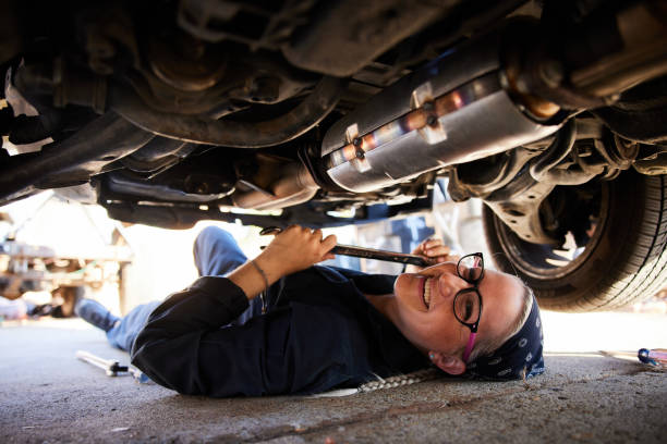 istock Smiling young female mechanic working under a car at her workshop 1398054386