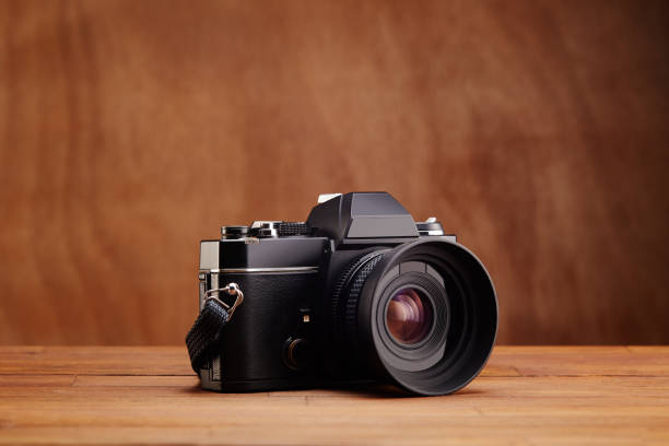 istock SLR Single-lens reflex professional camera on wooden table and background 1398054428