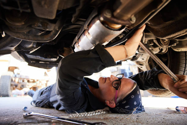 istock Female mechanic working on the underside of a car 1398054595