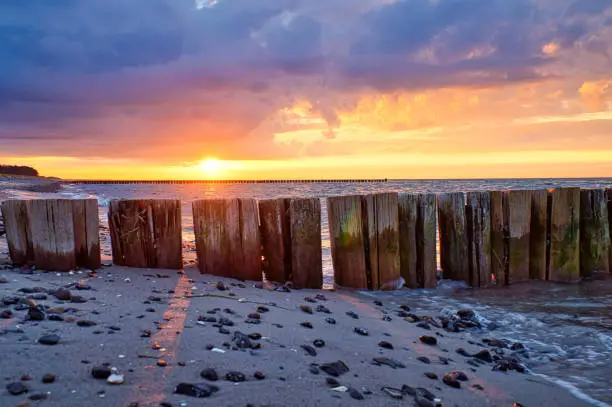 groynes jutting into the sea at sunset. Beach with stones in the foreground. taken in zingst on the darss. the perspective is directed to the horizon