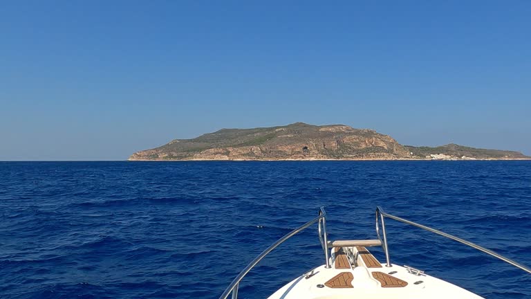 Bow of yacht cruising and approaching Levanzo Sicilian islan, Sicily in Italy. Slow-motion first-person view