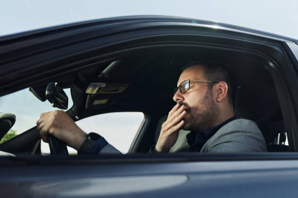 istock Tired businessman yawning while driving a car. 1398056947