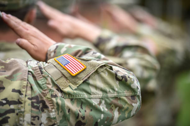 scatto di dettaglio con bandiera americana su uniforme da soldato, che dà il saluto d'onore durante la cerimonia militare - saluting armed forces military army foto e immagini stock