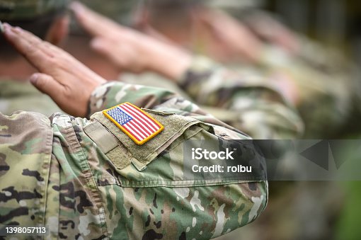 istock Detail shot with american flag on soldier uniform, giving the honor salute during military ceremony 1398057113