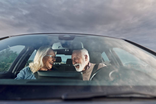 Cheerful mature couple talking while going on a road trip by car.
