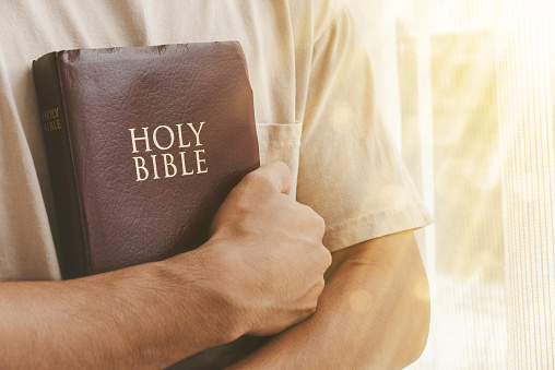 Man hugging the bible in the morning. Concept, faith, hope, trust in God.