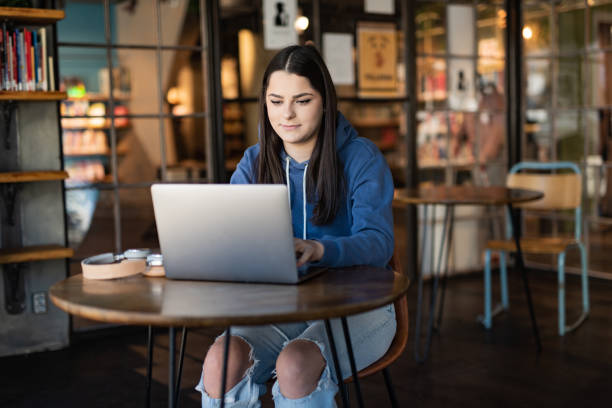 istock Young female student looking at laptop in University lobby 1398062924