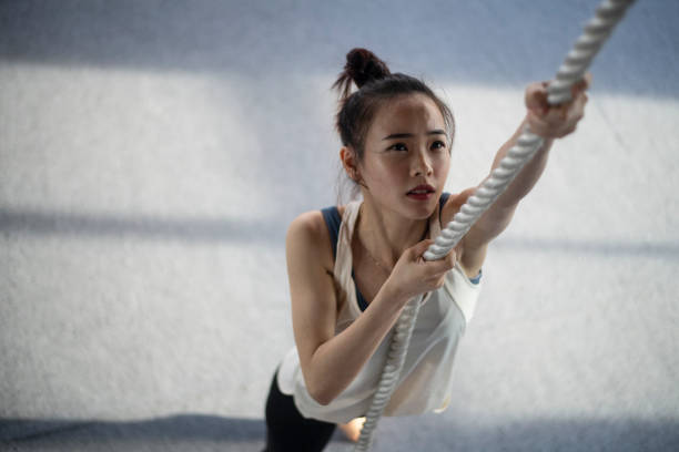 Asian Chinese Girl working out with battle rope in gym stock photo