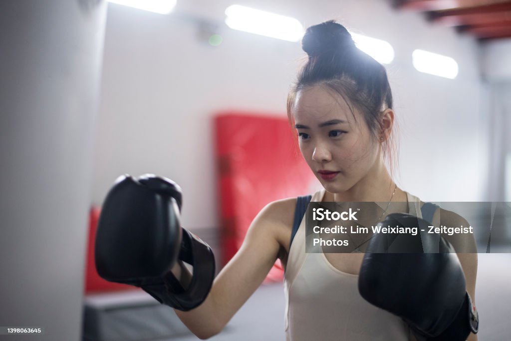 Asian Chinese Girl working out with boxing gloves and punching bag Muay Thai Stock Photo