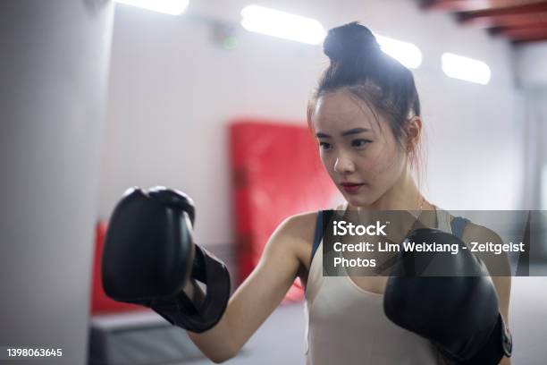 Asian Chinese Girl Working Out With Boxing Gloves And Punching Bag Stock Photo - Download Image Now