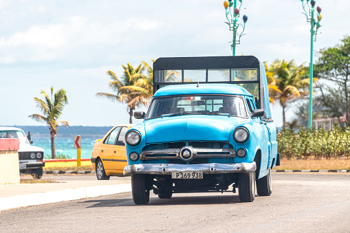 Varadero, Cuba - March 17, 2019: A man drives a vintage car that has been transformed to carry passengers for a fee. The practice is common and a popular mode of transportation for local people.