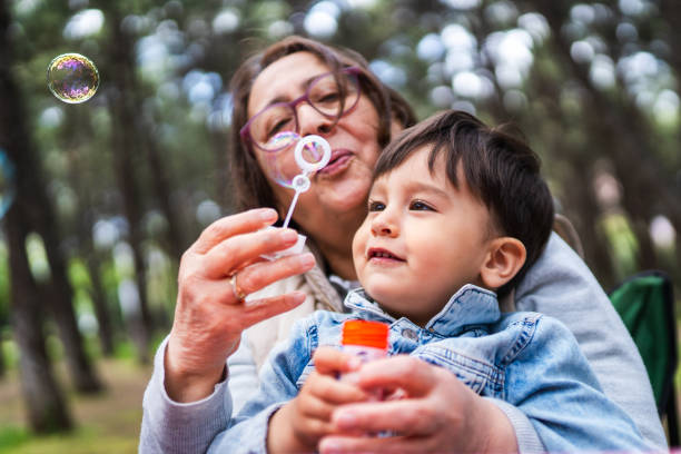 el niño y su abuela jugando juntos en el picnic - bubble wand bubble child playful fotografías e imágenes de stock