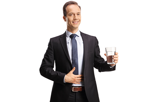 Businessman holding a glass of water and smiling isolated on white background
