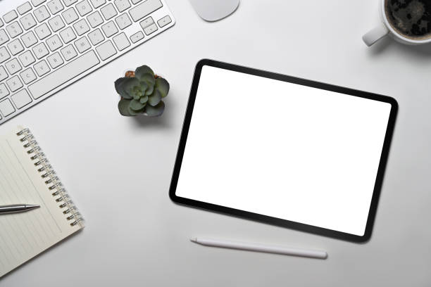 istock Top view digital tablet, notebook, coffee cup and succulent plant on white office desk. 1398069247