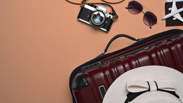 istock Above view suitcase with sunglasses, camera, passport and hat on beige background. Preparing for the summer vacations. 1398069268
