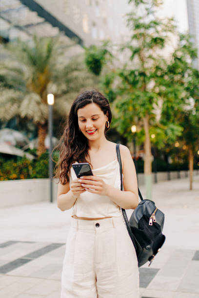 istock Woman using her smart phone on the street 1398070483
