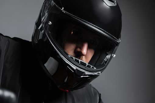 Biker in the helmet close up portrait, riding motorcycle, studio shot, indoors. Studio shot. Close up, horizontal.