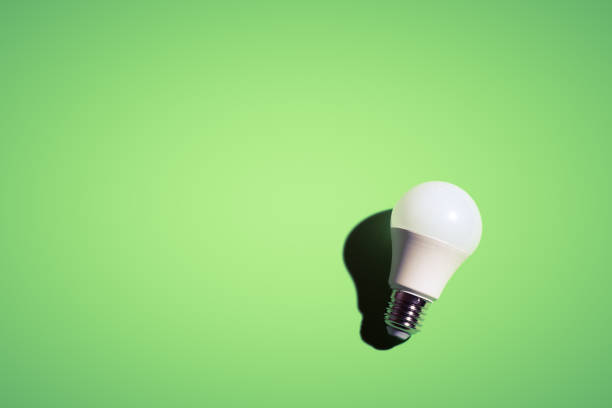 istock White lightbulb on green background under the bright light with black shadow. 1398070667