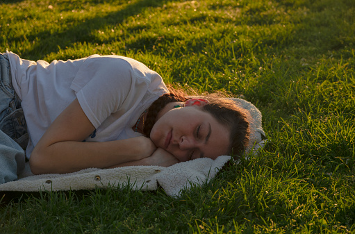 Teenage girl sleeping on grass during sunset