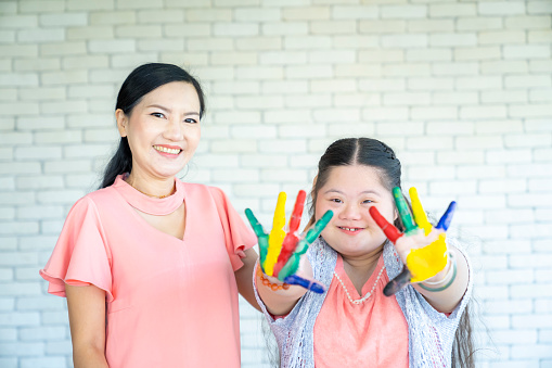 down syndrome teenage girl showing painted hands  with mom