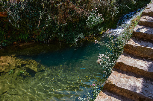 Crystal clear water next to the stairs in the course of the river at the Tobera waterfalls, Burgs, Spain