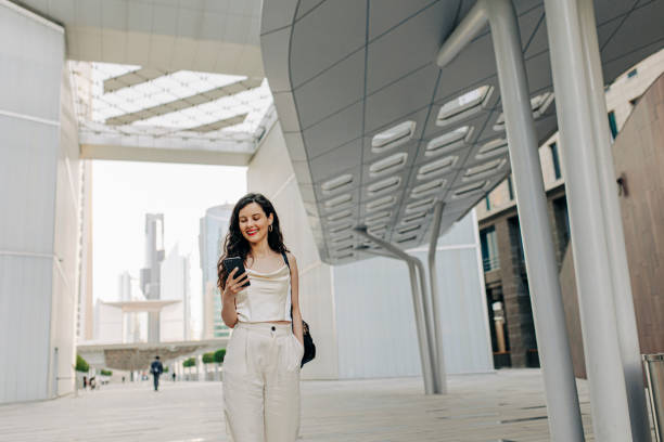 istock Woman using her smart phone on the street 1398073636