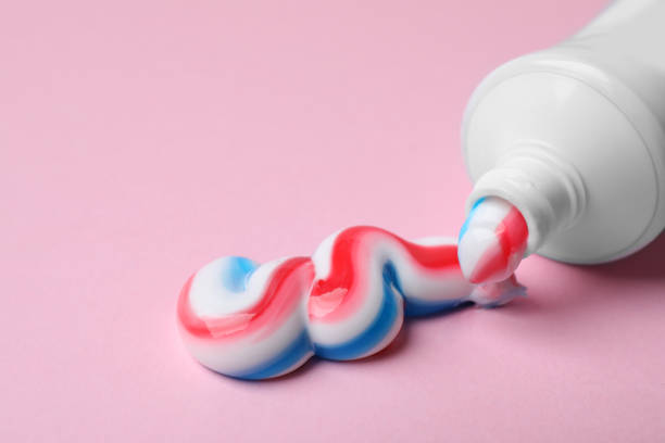istock Tube with squeezed out toothpaste on pink background, closeup 1398075195