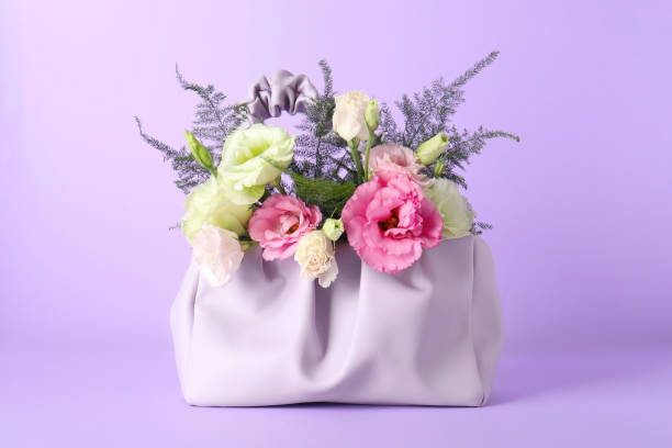 Stylish women's bag with beautiful flowers on violet background