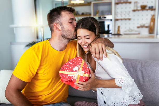 istock Happy couple with gift box hugging at home 1398075725