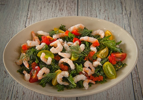 Cooked arctic shrimp with different kind of salad ingredients such as cherry tomatoes and bell pepper.