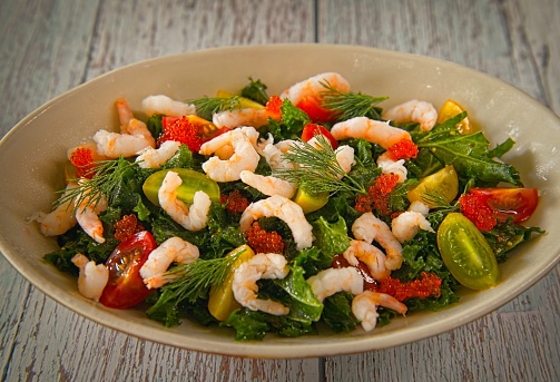 Cooked arctic shrimp with different kind of salad ingredients such as cherry tomatoes and bell pepper.