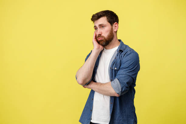 istock Upset man thoughtfully holding his beard on yellow background 1398077017