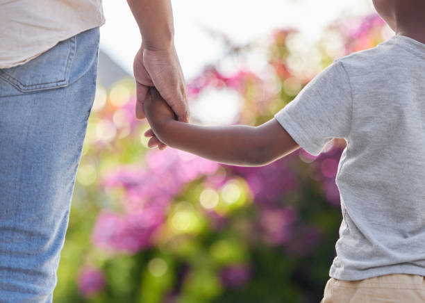 primo piano padre e figlio che si tengono per mano mentre camminano fuori in giardino. un grande modello e mentore per il suo bambino. un figlio guarderà sempre con ammirazione e seguirà le orme del padre. - holding hands human hand child mother foto e immagini stock