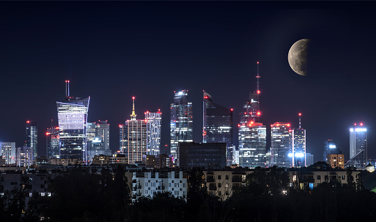 Night view of Warsaw downtown with beautiful moon in the sky. Warsaw is a capital of Poland. Modern european city