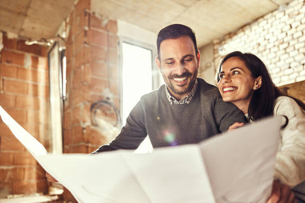 Happy couple analyzing plans at their renovating apartment.